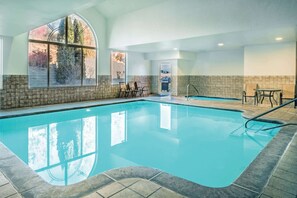 A swimming pool with a view of trees through a large arched window, a barbecue grill, and a seating area with tables and chairs. - La Quinta Inn & Suites by Wyndham Moscow Pullman (Moscow)
