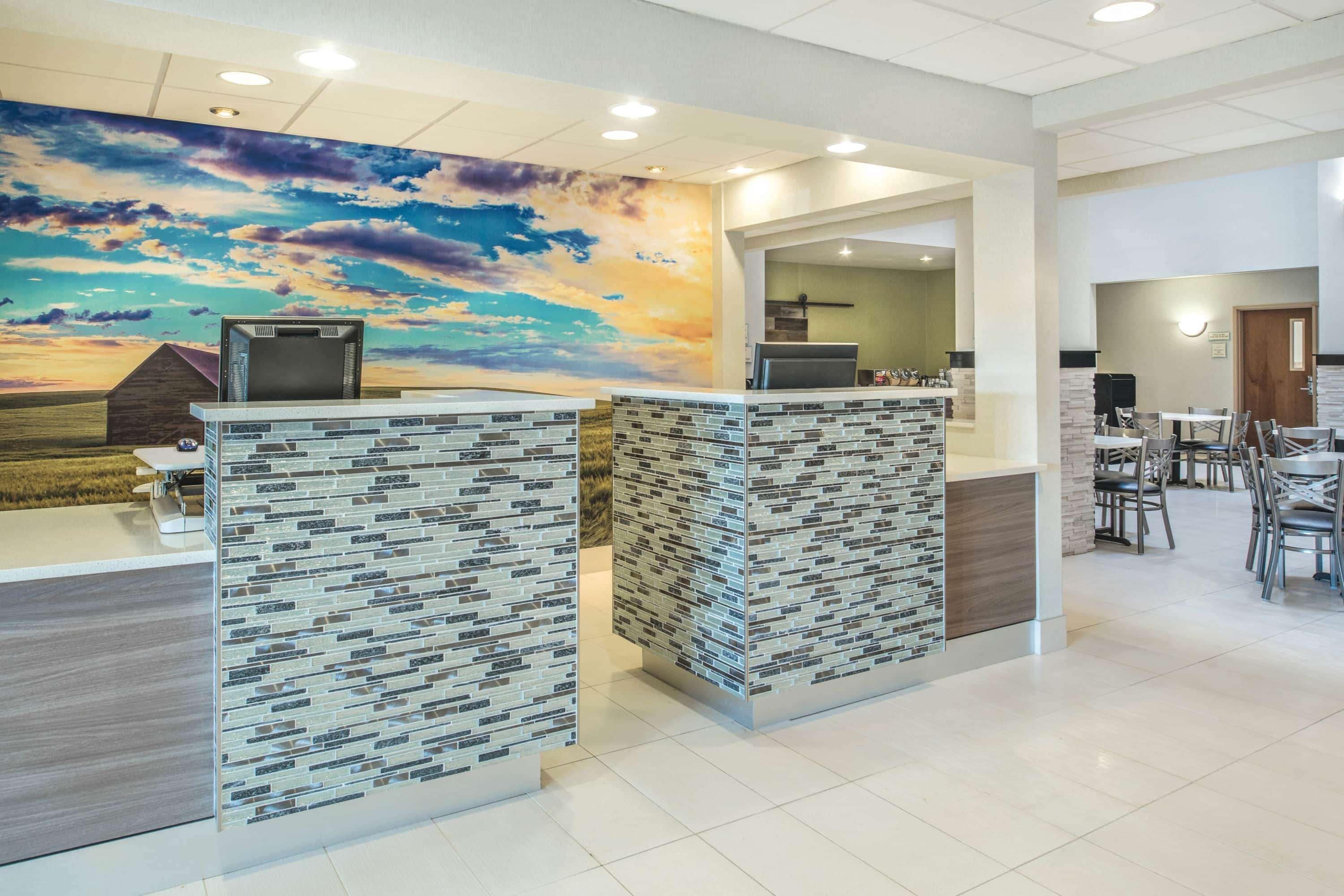A reception area with a modern design, including a large mural, a reception desk, and a seating area with tables and chairs.