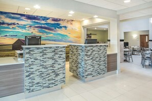 A reception area with a modern design, featuring a large mural of a sunset, a reception desk, and a seating area with tables and chairs. - La Quinta Inn & Suites by Wyndham Moscow Pullman (Moscow)