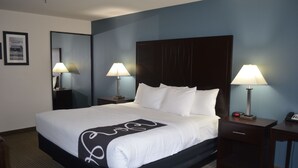 Una camera d'albergo con un letto grande, due comodini con lampade, un tavolino con il telefono e un quadro appeso al muro.