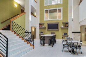 A spacious interior with a staircase, a dining area with multiple tables and chairs, and a flat-screen TV mounted on the wall. - La Quinta Inn & Suites by Wyndham Moscow Pullman (Moscow)