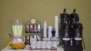 Un angolo caffè con una macchina da caffè, tazze e un cestino con cialde per il caffè.