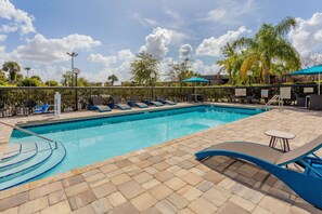 Una piscina al aire libre, sillones reclinables de piscina