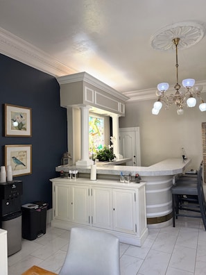 A kitchen with white cabinets, a marble countertop, a chandelier, and a stained glass window.