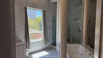 Een badkamer met een bad, douche en een raam voorzien van gordijnen.