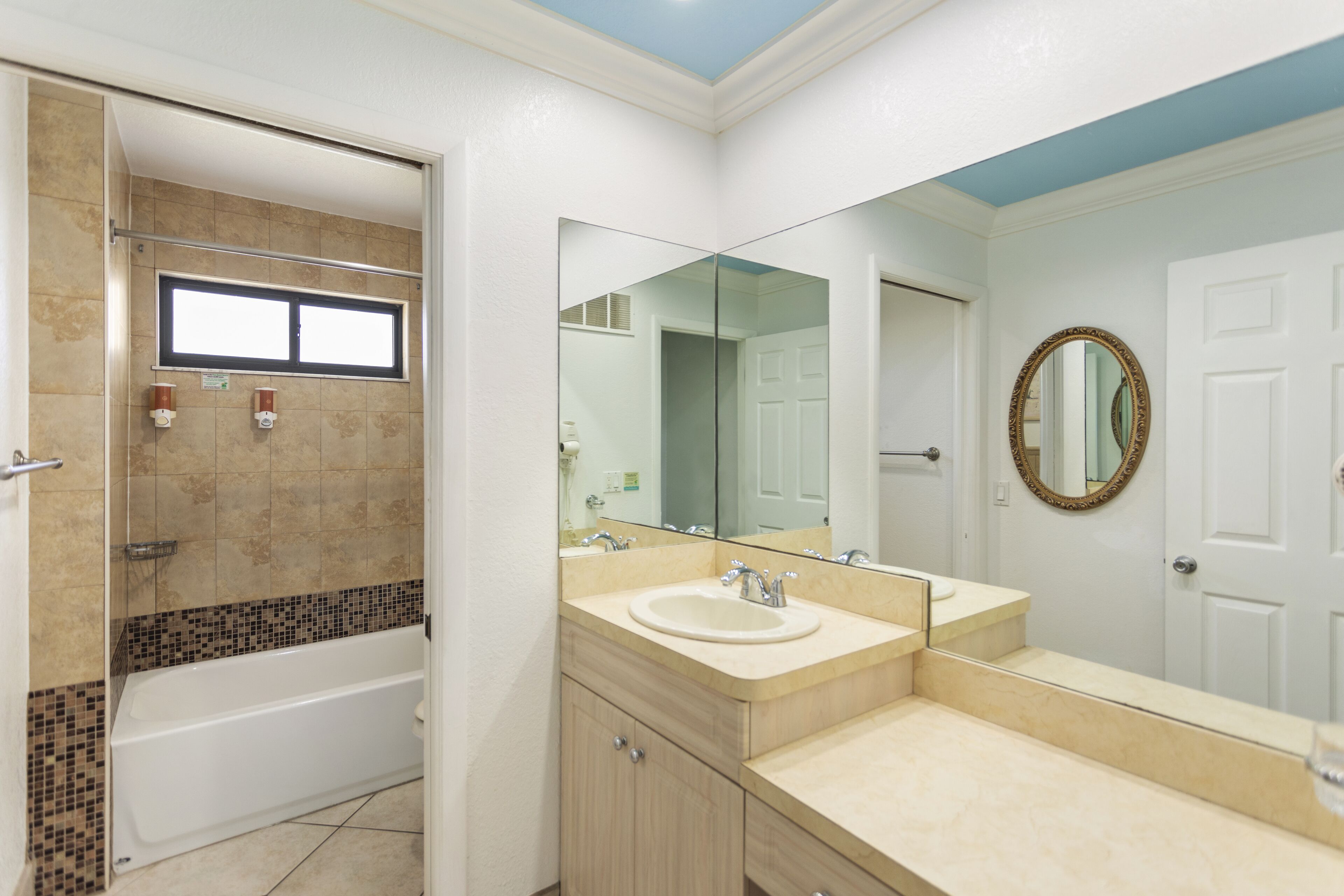 A bathroom with a bathtub, a sink, and a large mirror.
