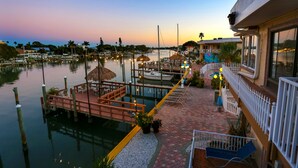 A waterfront area with docks, boats, and a pathway leading to a building with a balcony.