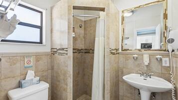 A bathroom with a shower, toilet, sink, and a mirror.