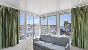 A room with a grey sofa, large windows, and green curtains.