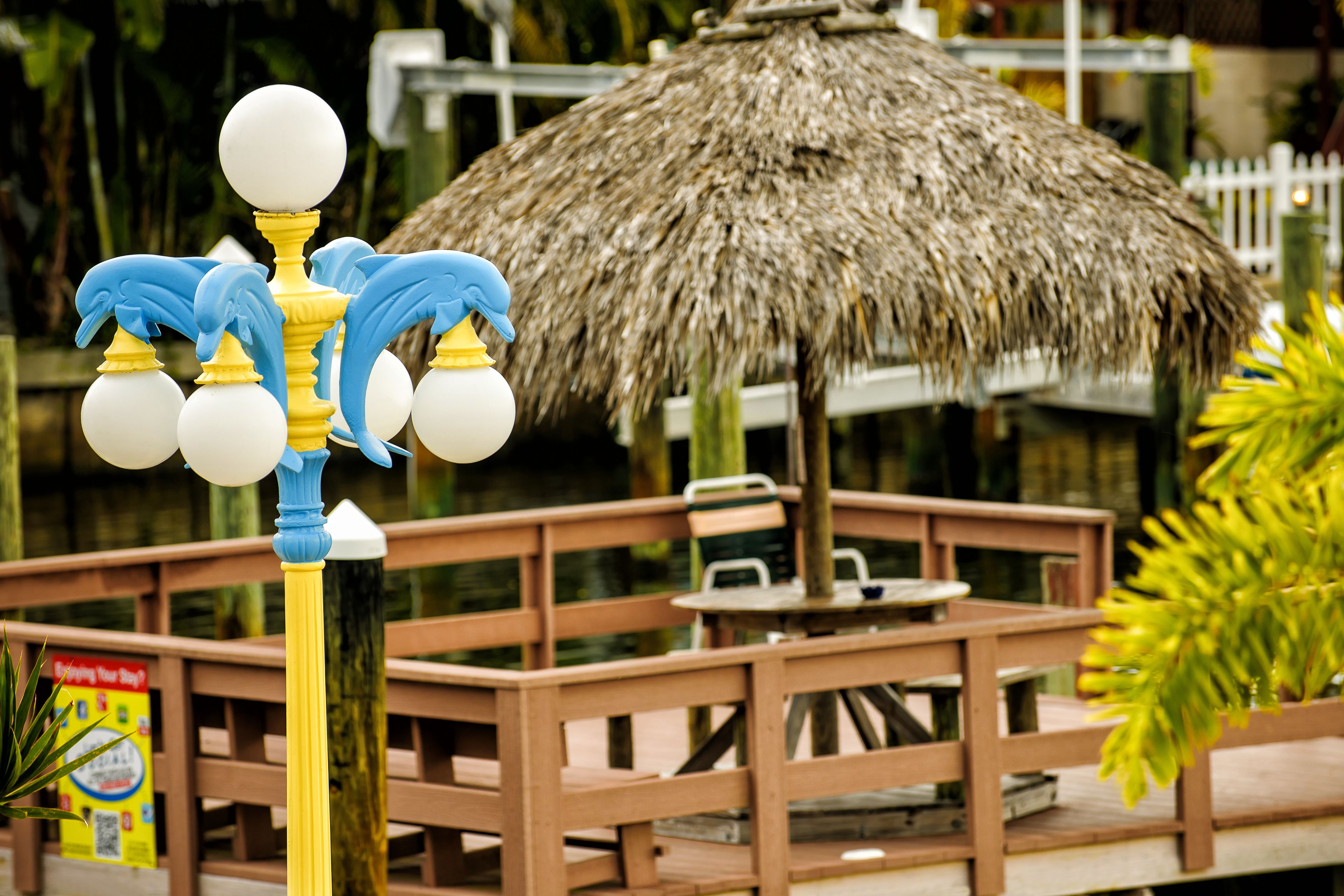 A wooden deck with a thatched umbrella, a small table, and chairs.