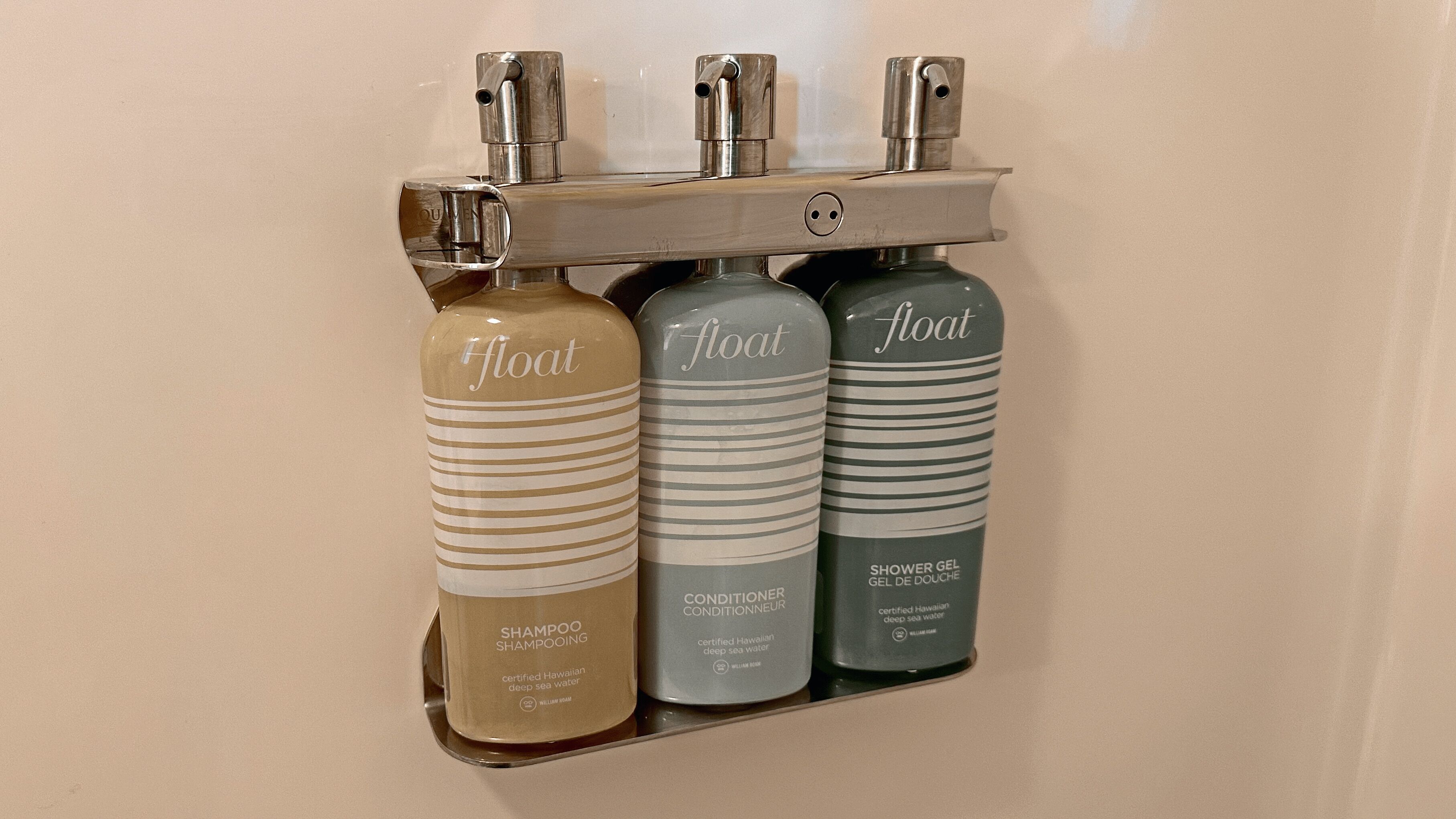 Een badkamerschaar met drie flessen 'float' producten: shampoo, conditioner en douchegel.