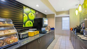 A modern kitchen area with a self-service station, including a toaster, a coffee machine, and a display of fresh produce.