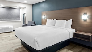 Una camera d'albergo moderna con un letto grande, comodini integrati e un lampadario fissato alla parete.