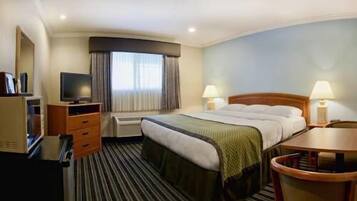 A hotel room with a bed, a desk, a television, and a window with curtains.
