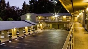A motel with a central parking area and multiple buildings with attached garages. - Hotel Parmani (Palo Alto)