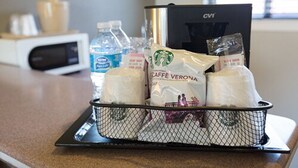 A tray with a coffee maker, bottled water, and Starbucks coffee bags on a kitchen counter. - Hotel Parmani (Palo Alto)