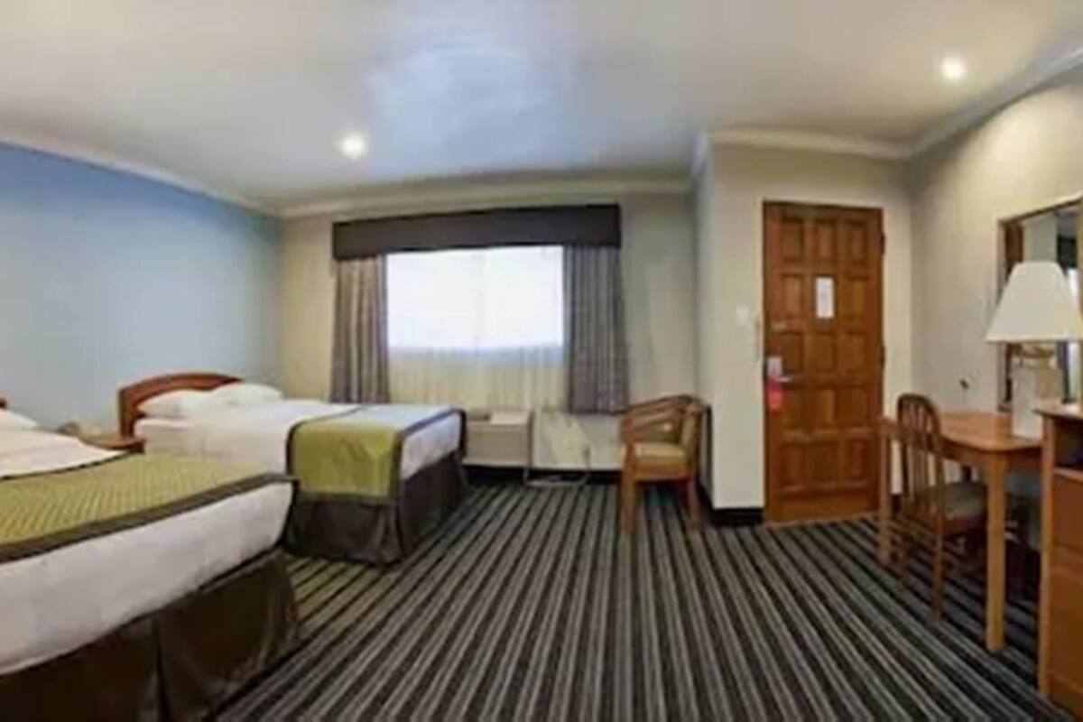 Una habitación de hotel con dos camas, televisión, escritorio y una silla.