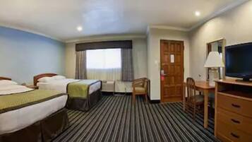 Una habitación de hotel con dos camas, televisión, escritorio y una silla.