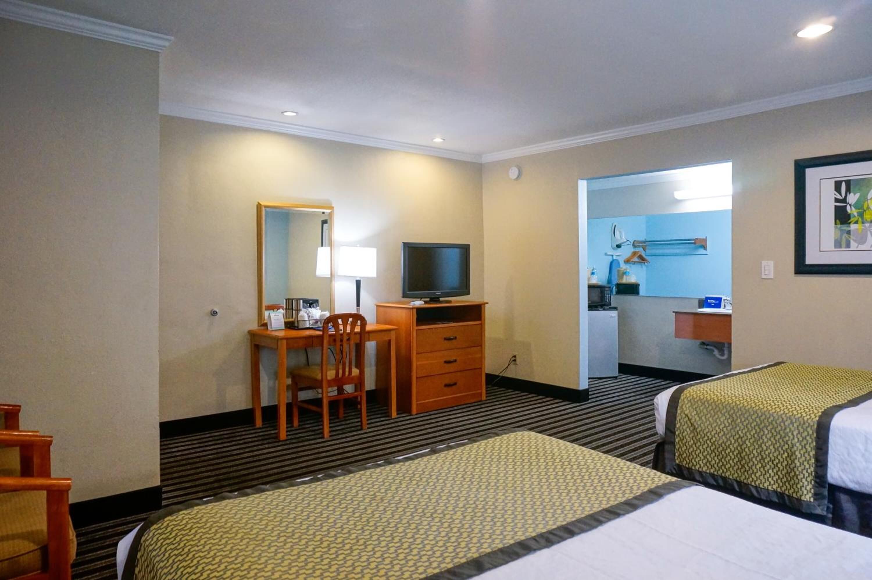 Ett hotellrum med två sängar, ett skrivbord med en stol, en tv och ett badrum som syns genom en öppen dörr.