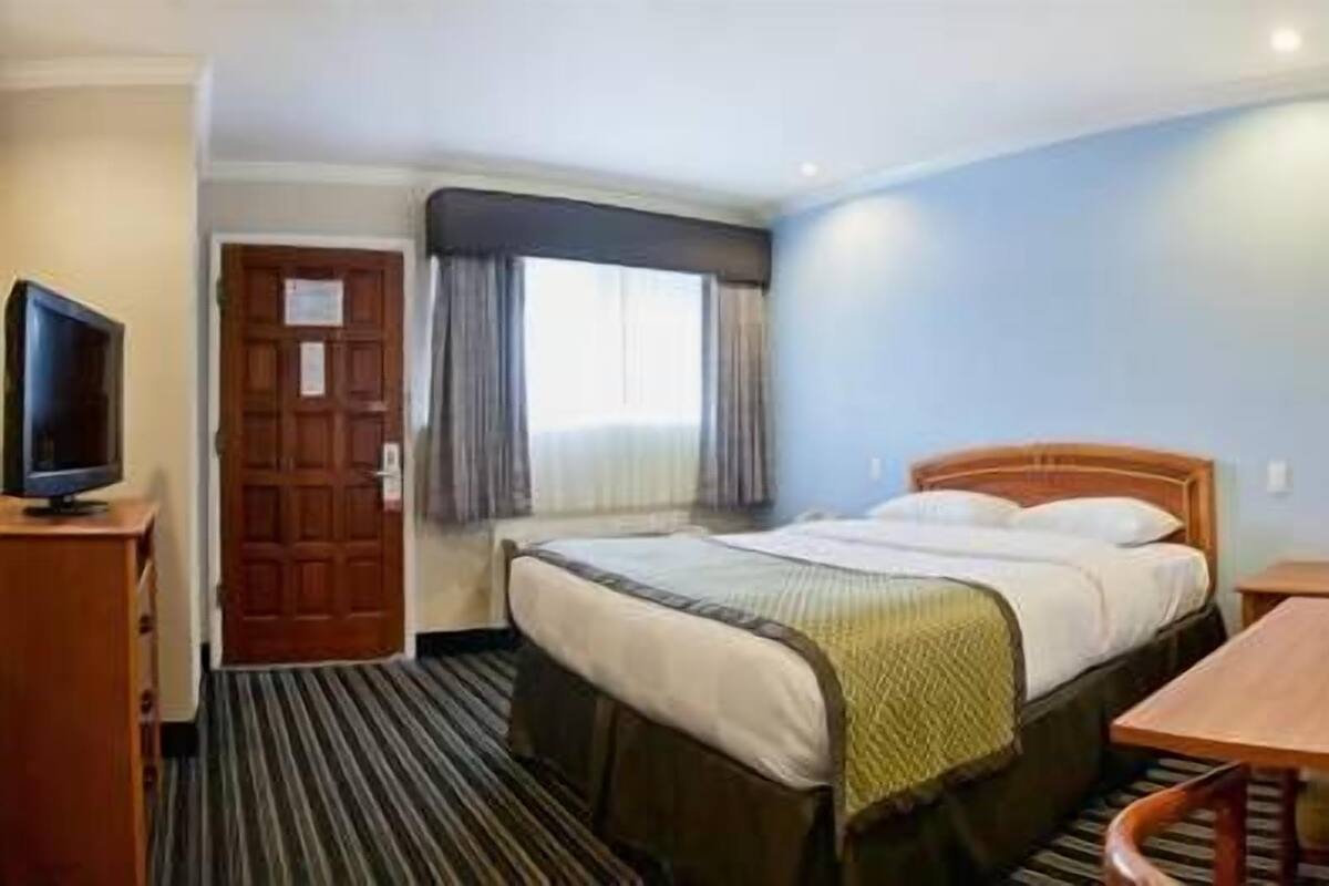 Una habitación de hotel con cama, televisor, escritorio y silla.