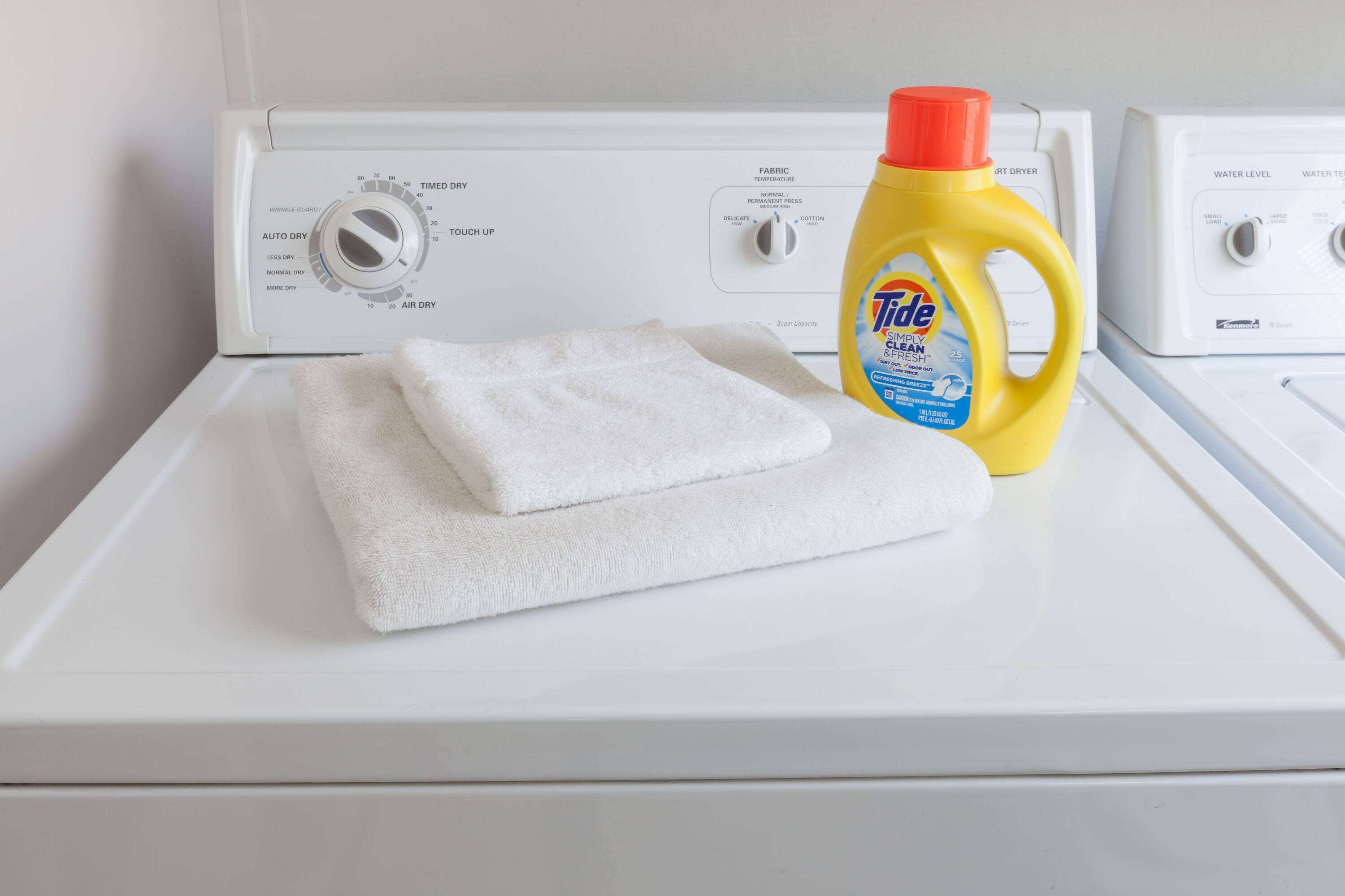 En vit tvättmaskin med en flaska tvättmedel från märket Tide ovanpå.