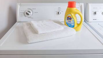 En vit tvättmaskin med en flaska tvättmedel från märket Tide ovanpå.