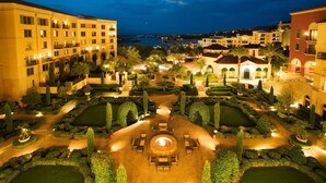 A courtyard with a central fire pit, surrounded by seating and well-manicured gardens, overlooking a body of water and adjacent buildings. - Hilton Lake Las Vegas Resort and Spa (Henderson)