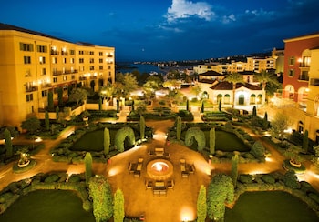 A wedding aisle with white draped trees and a purple floral carpet leading to a building with balconies. at Hilton Lake Las Vegas Resort and Spa