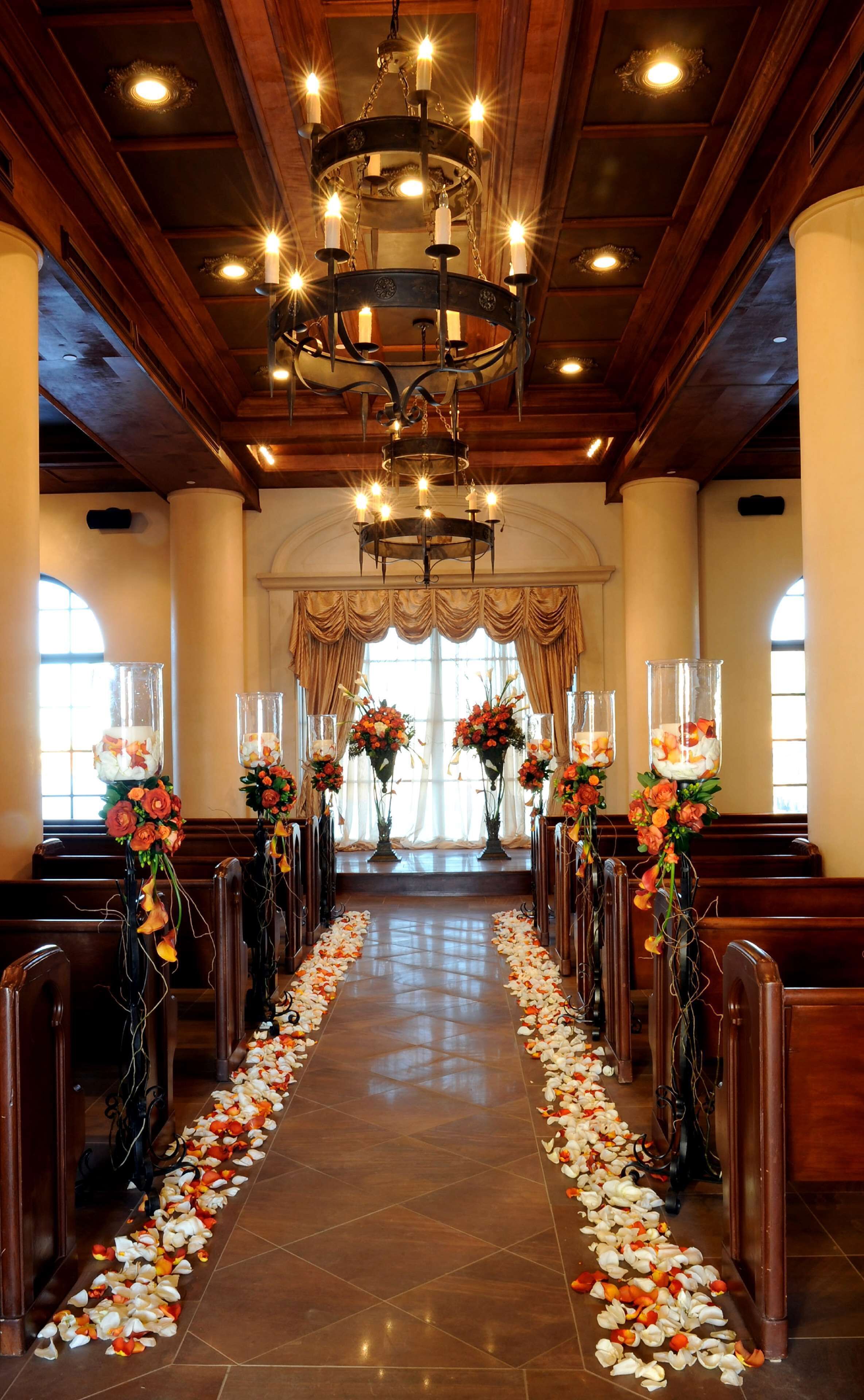 A church interior with pews, a flower-decorated aisle, and a chandelier.