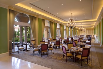 A grand room with a grand piano, a chandelier, and large windows offering a view of buildings outside. at Hilton Lake Las Vegas Resort and Spa