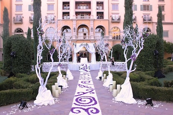 An outdoor dining area with tables set for a meal, surrounded by a building with multiple balconies and arched windows. at Hilton Lake Las Vegas Resort and Spa