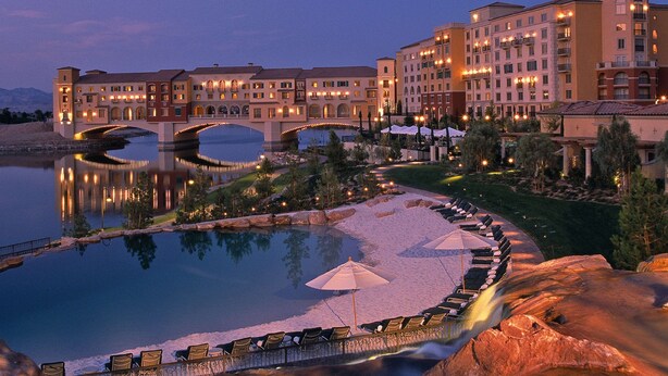 A hotel with a large pool, a bridge, and multiple buildings with balconies. - Hilton Lake Las Vegas Resort and Spa (Henderson)