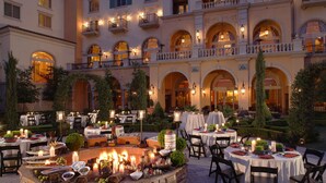 An outdoor dining area with tables set for a meal, surrounded by a building with multiple balconies and arched windows. - Hilton Lake Las Vegas Resort and Spa (Henderson)