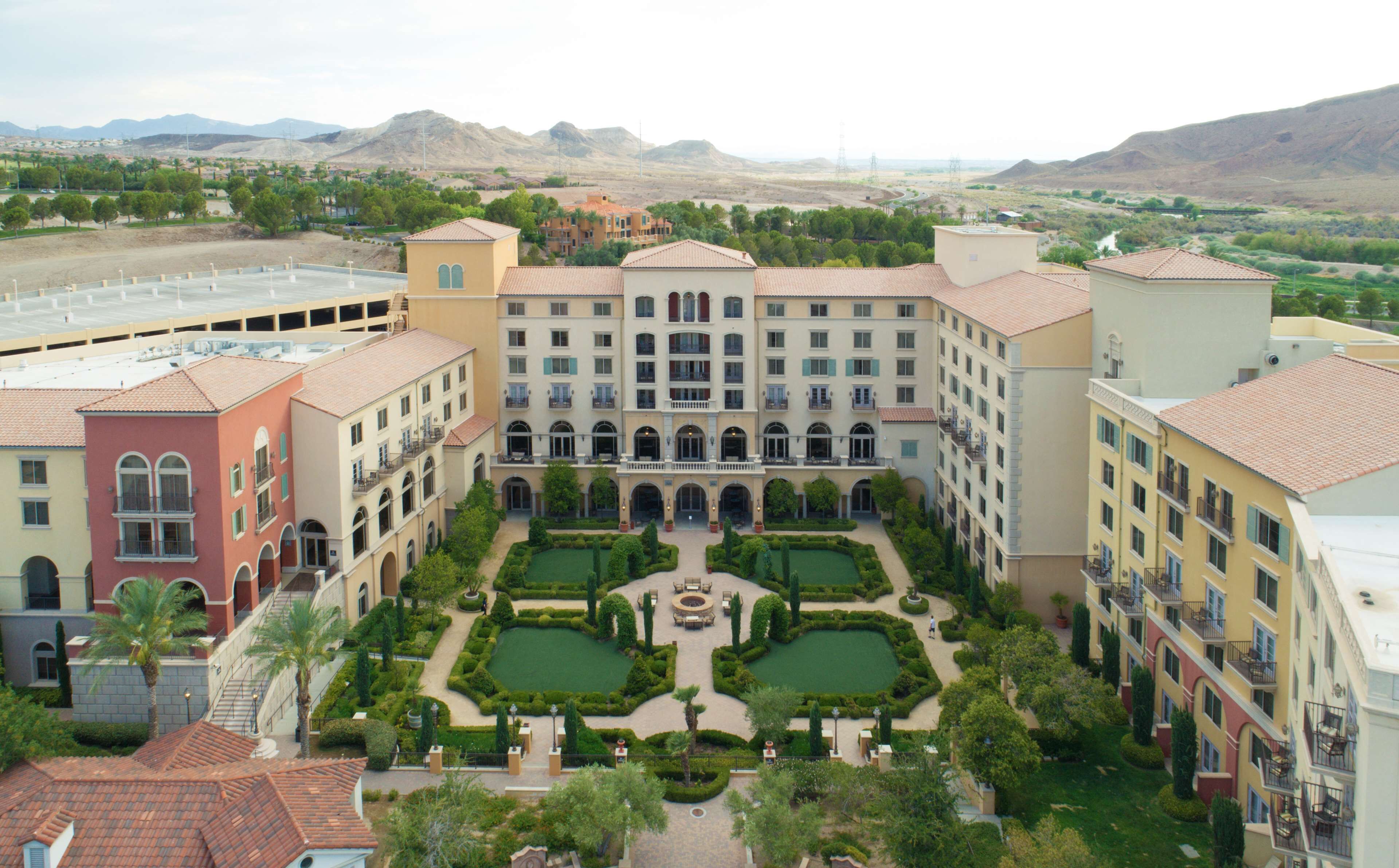 A hotel courtyard with a central fountain, surrounded by manicured gardens and multiple buildings with balconies.