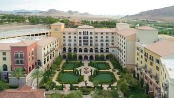 A hotel courtyard with a central fountain, surrounded by manicured gardens and multiple buildings with balconies.