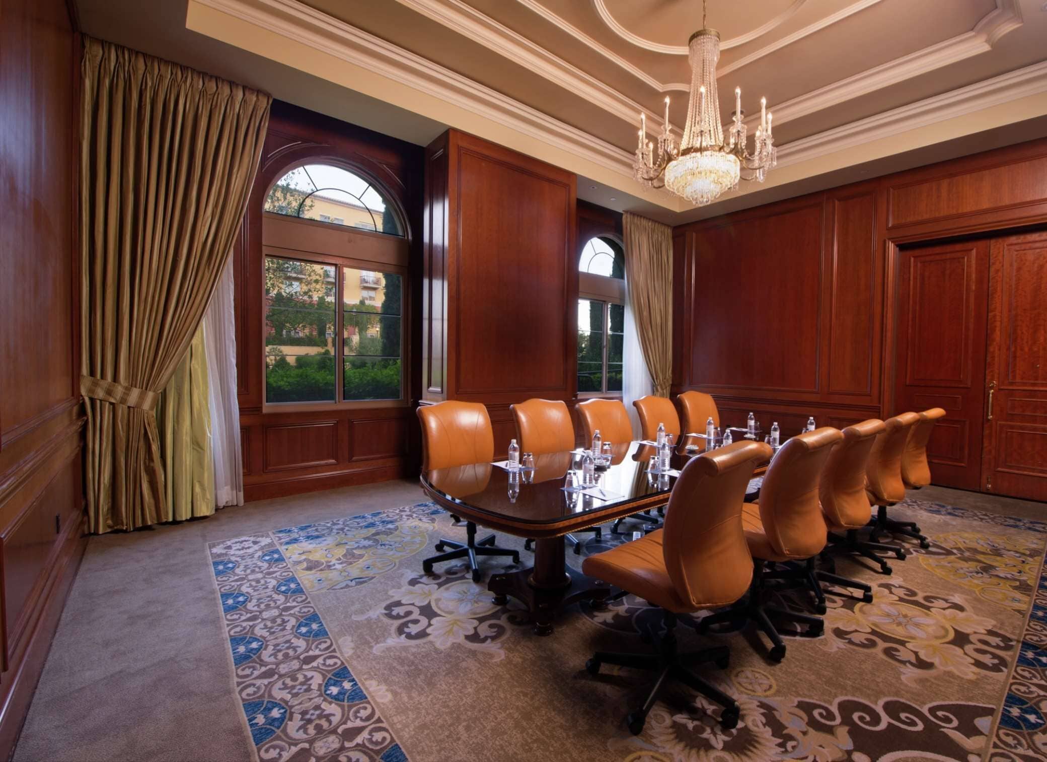 A conference room with a large table, leather chairs, and a chandelier.
