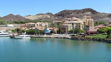 A marina with boats docked, a waterfront promenade, and a cluster of Mediterranean-style buildings with balconies.