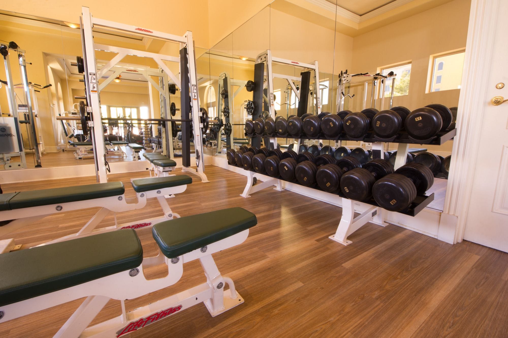 Une salle de sport équipée de matériel de musculation, de bancs et d’un porte-haltères.