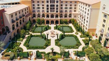 A courtyard with a central fountain, surrounded by manicured gardens and multi-story buildings with balconies.
