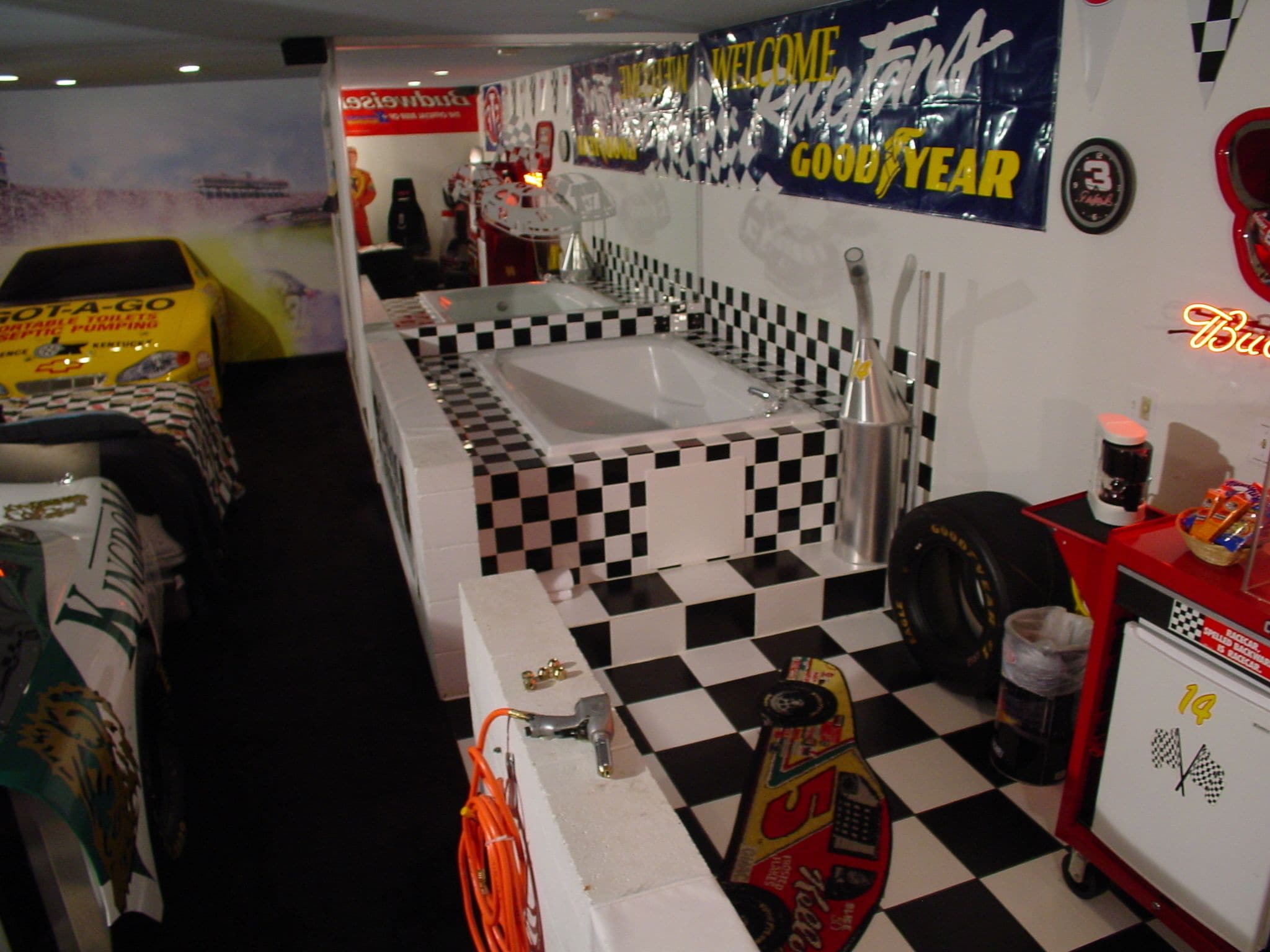 Une salle de bain sur le thème des courses automobiles, avec un sol à carreaux, une grande baignoire et divers objets de collection liés à ce sport.