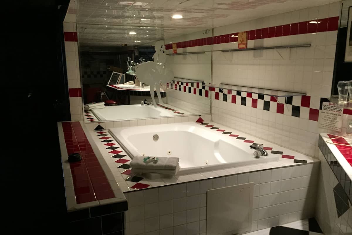 A bathroom with two large tubs, a mirror, and a tiled floor.