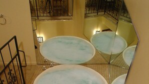 A bathroom with a large mirror, a bathtub, and a small table with a chair. - Wildwood Inn Tropical Dome & Theme Suites (Florence)