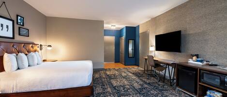 Ein Hotelzimmer mit einem großen Bett, einem Schreibtisch, einem Fernseher und einer Mikrowelle.