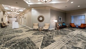A spacious hotel lobby with a patterned carpet, seating areas, and a chandelier. - Radisson Hotel Fairview Heights - St. Louis (Fairview Heights)
