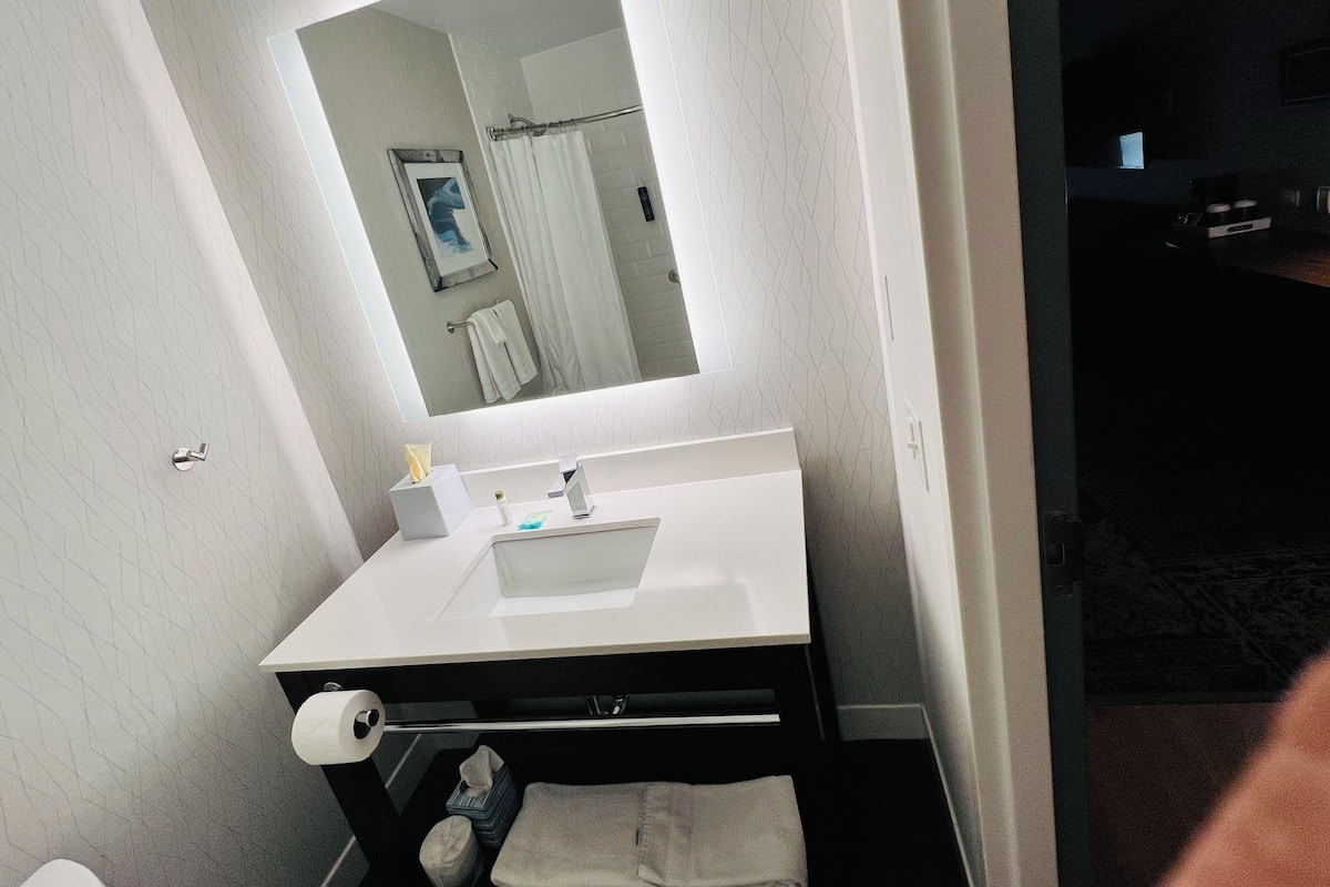 A bathroom with a white sink, a mirror, a towel rack, and a toilet.