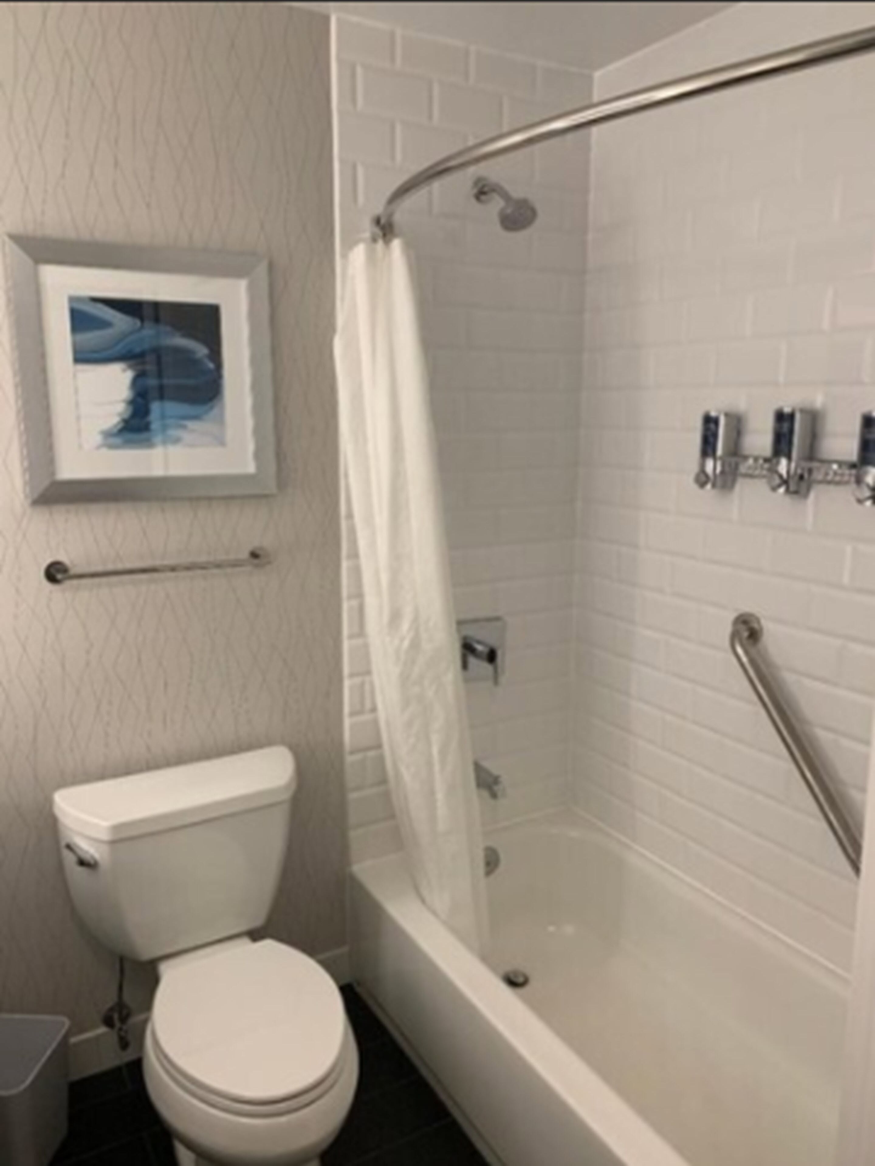 A bathroom with a white toilet, a shower with a glass door, and a tiled wall.