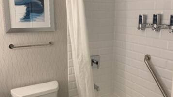 A bathroom with a white toilet, a shower with a glass door, and a tiled wall.