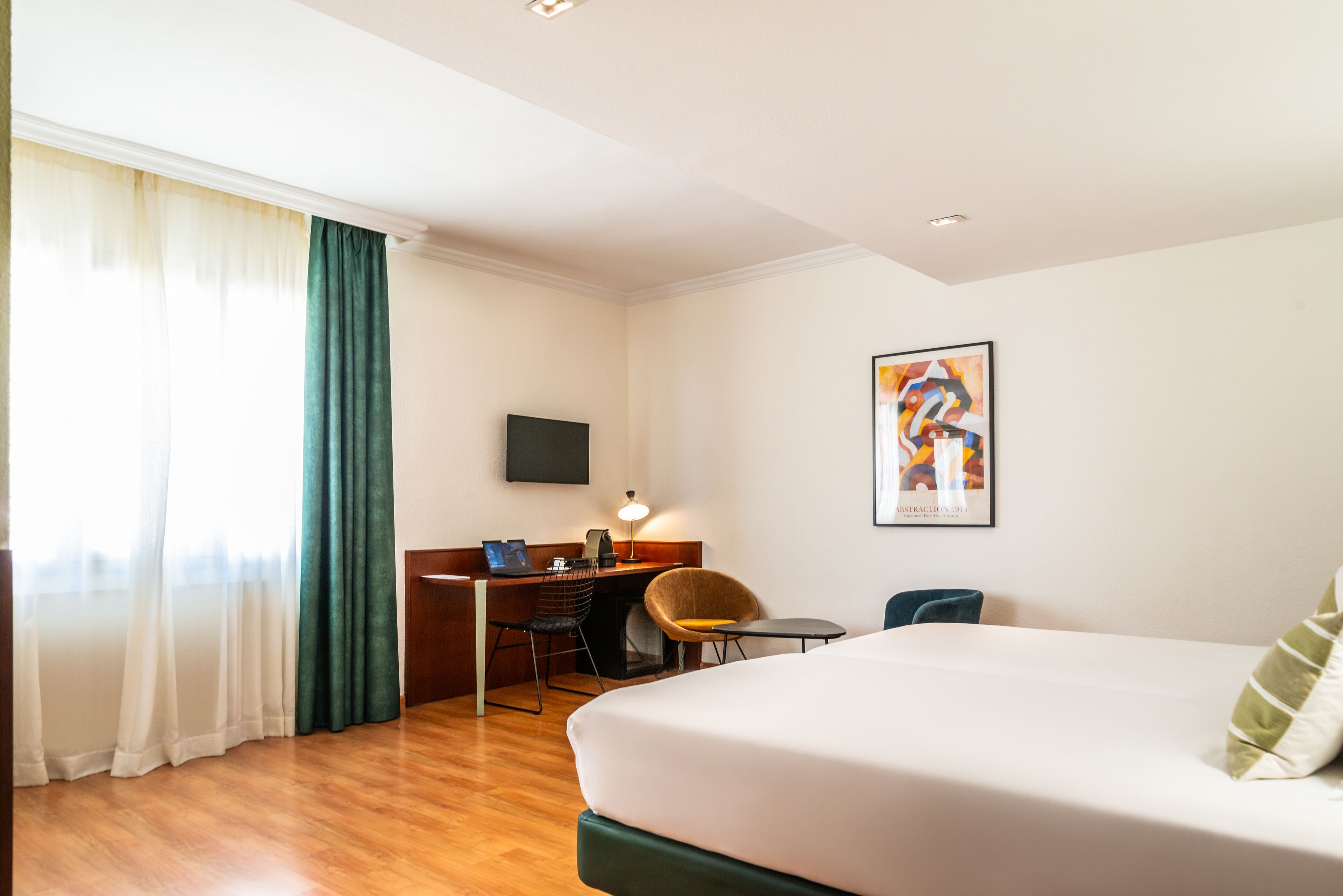 Habitación de hotel con cama, escritorio, silla y un cuadro en la pared.
