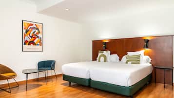Una habitación de hotel moderna con una cama grande, dos mesitas de noche, una silla y un cabecero de madera.