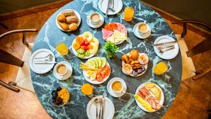 A marble table with breakfast items including eggs, sausages, and fruit. - Hôtel Casón del Tormes by HappyCulture (Madrid)